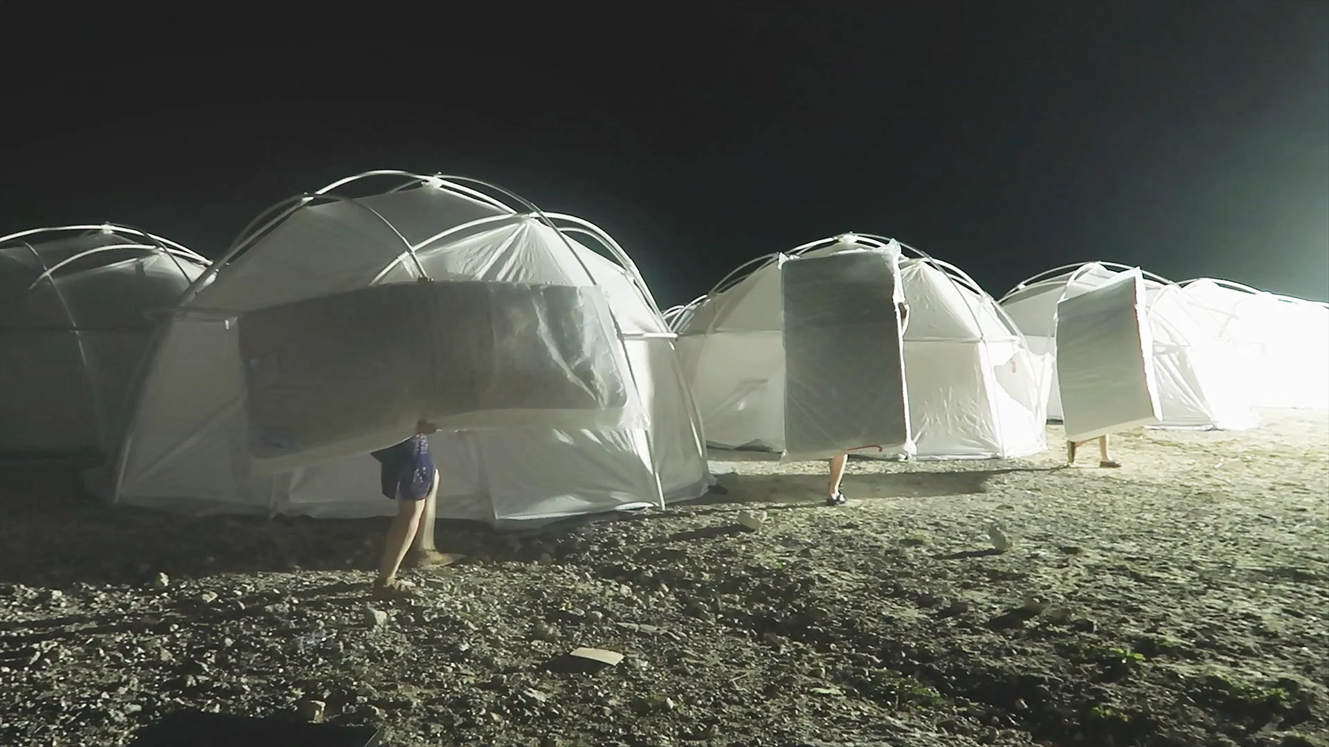 Relief tents set up for Fyre Festival attendees at night, showing white dome structures on barren ground